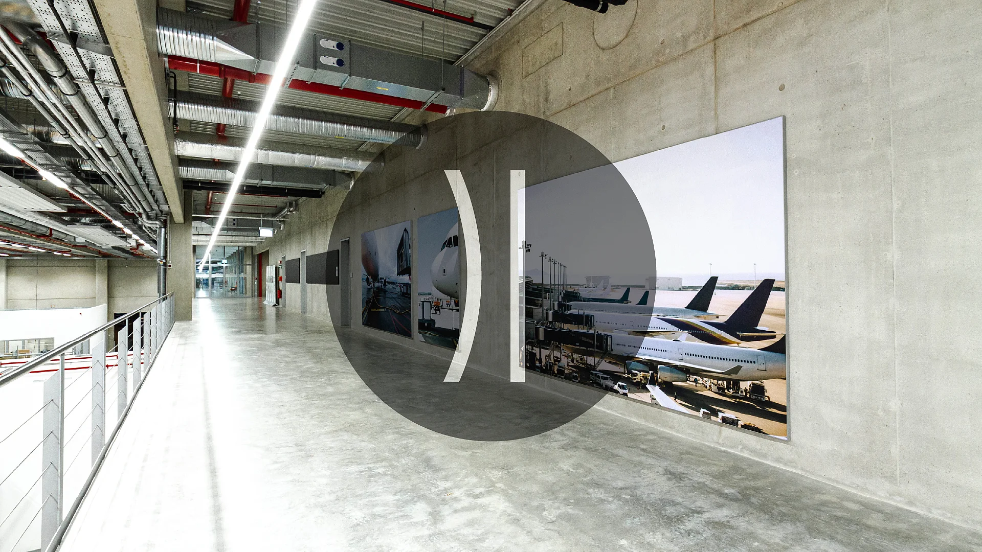 GFAG-Projektreferenz bei Recaro als Produktbeispiel für die Kategorie Wand: Ein großformatiges, bedrucktes Akustikwandbild mit einem Flugzeugmotiv an einer Sichtbetonwand. Das raumakustische Element reduziert effektiv den Nachhall im langen, modernen Flur- und Galeriebereich mit offener Industriedecke.