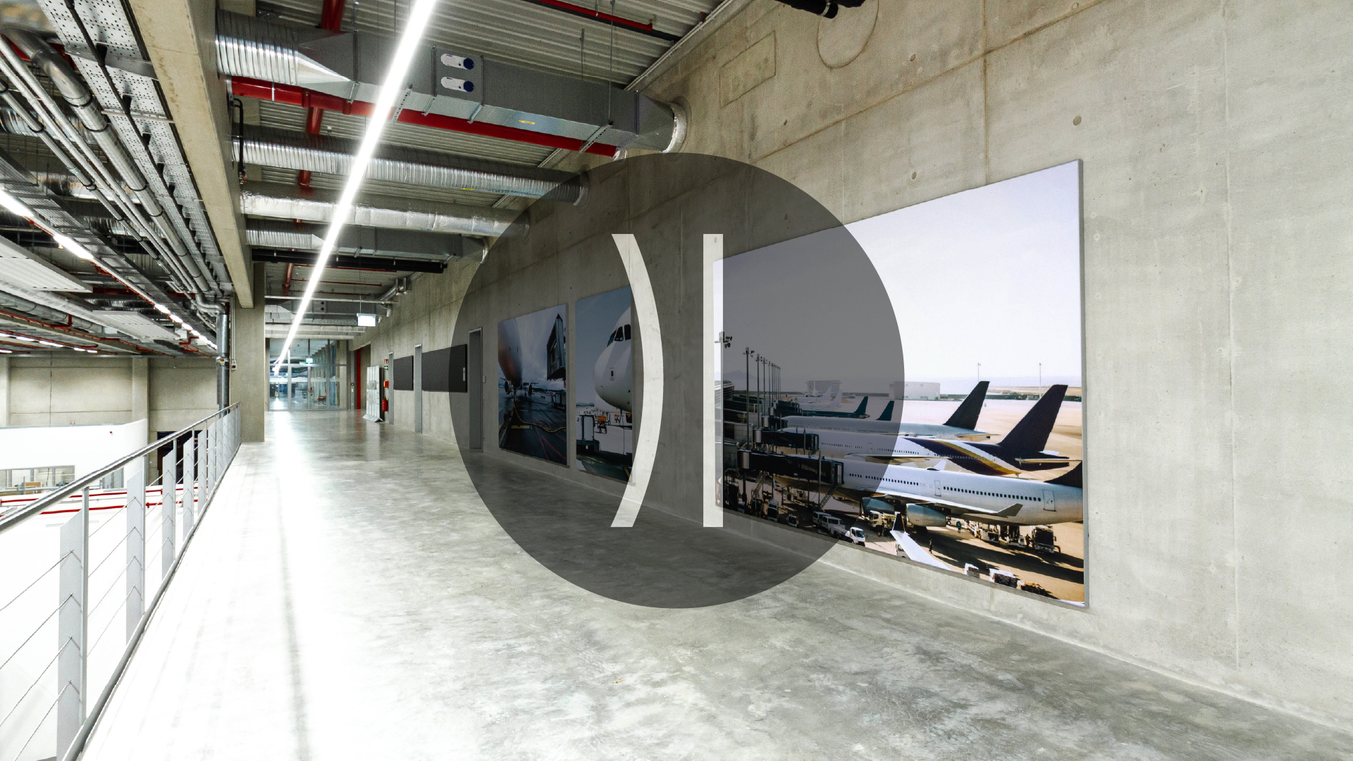 GFAG-Projektreferenz bei Recaro als Produktbeispiel für die Kategorie Wand: Ein großformatiges, bedrucktes Akustikwandbild mit einem Flugzeugmotiv an einer Sichtbetonwand. Das raumakustische Element reduziert effektiv den Nachhall im langen, modernen Flur- und Galeriebereich mit offener Industriedecke.